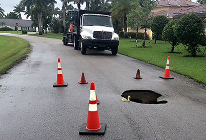 Mike Mann Construction white truck on an emergency response to sinkhole on the road
