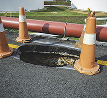 Sinkhole on the road with construction cones around it