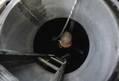 man climbing down a latter into a sewer pipe