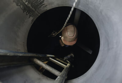 man climbing down a later into a sewer line